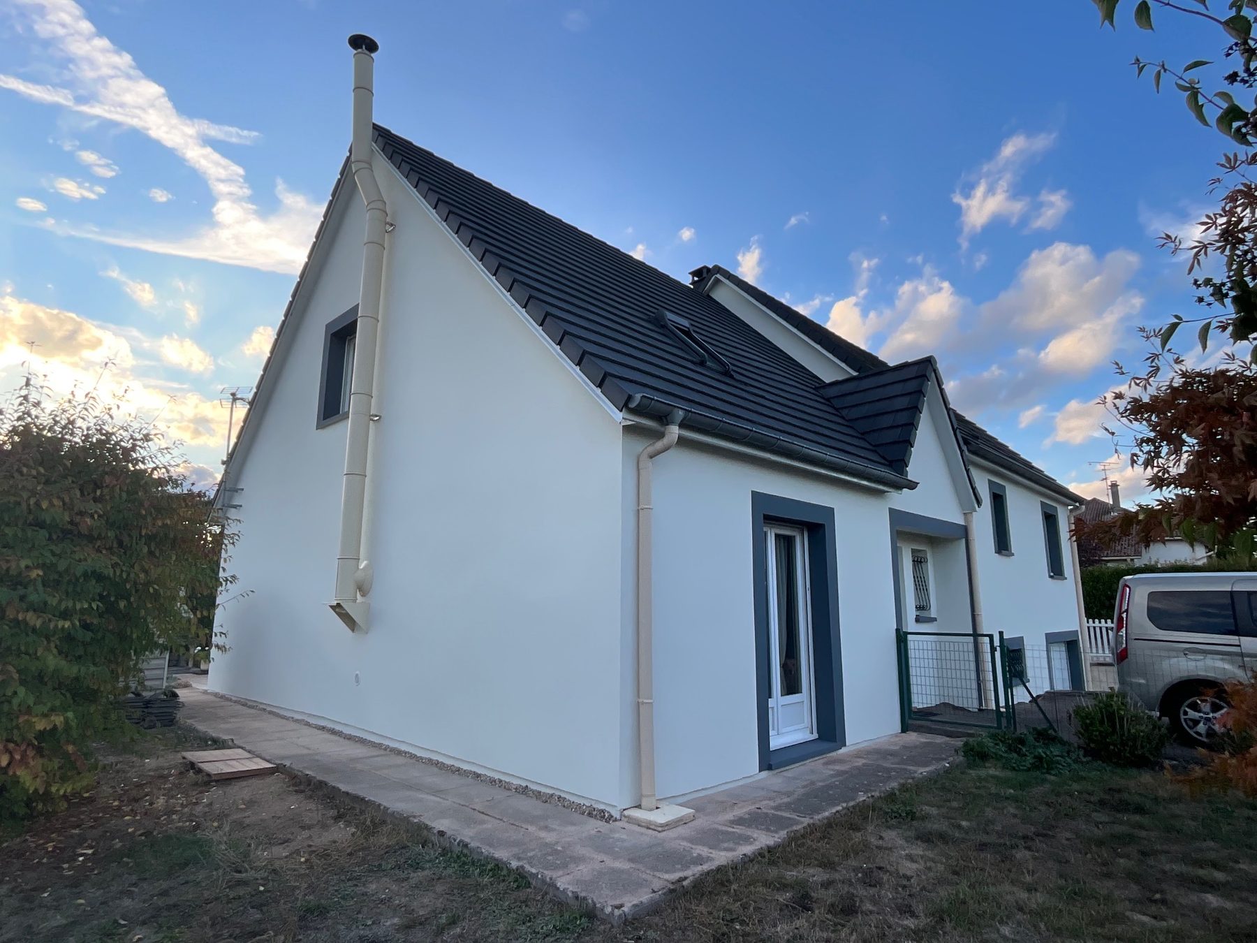 Maison aux façades blanches, toit anthracite, ciel du soir